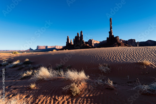 Totem Pole Rock Formation and sand dunes in Monument Valley, United States during sunset