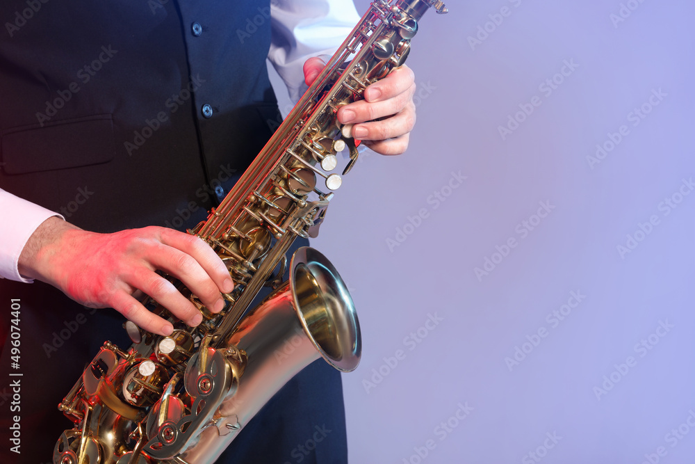 Obraz premium Man in elegant outfit playing saxophone on color background, closeup. Space for text