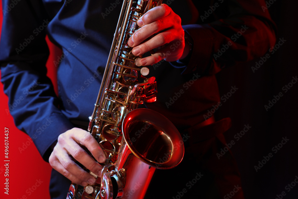 Obraz premium Man with saxophone on dark background, closeup