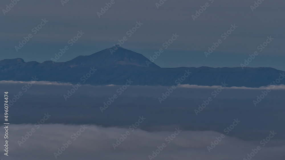 Distant view of island Tenerife with Mount Teide (3,715 m) above a sea of clouds viewed from Tamadaba Natural Park in the mountains of Grand Canaria.