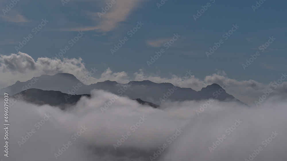 View of the silhouettes of mountains on the western coast of island Gran Canaria, Spain disappearing in a sea of clouds in winter season. View of the silhouettes of mountains on the western coast of island Gran Canaria, Spain disappearing in a sea of clouds in winter season.