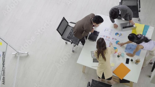 A group of Asian businessmen stand at a meeting about the company's earnings. Plan work to achieve successful results. at the desk of the company Taken from above from a height