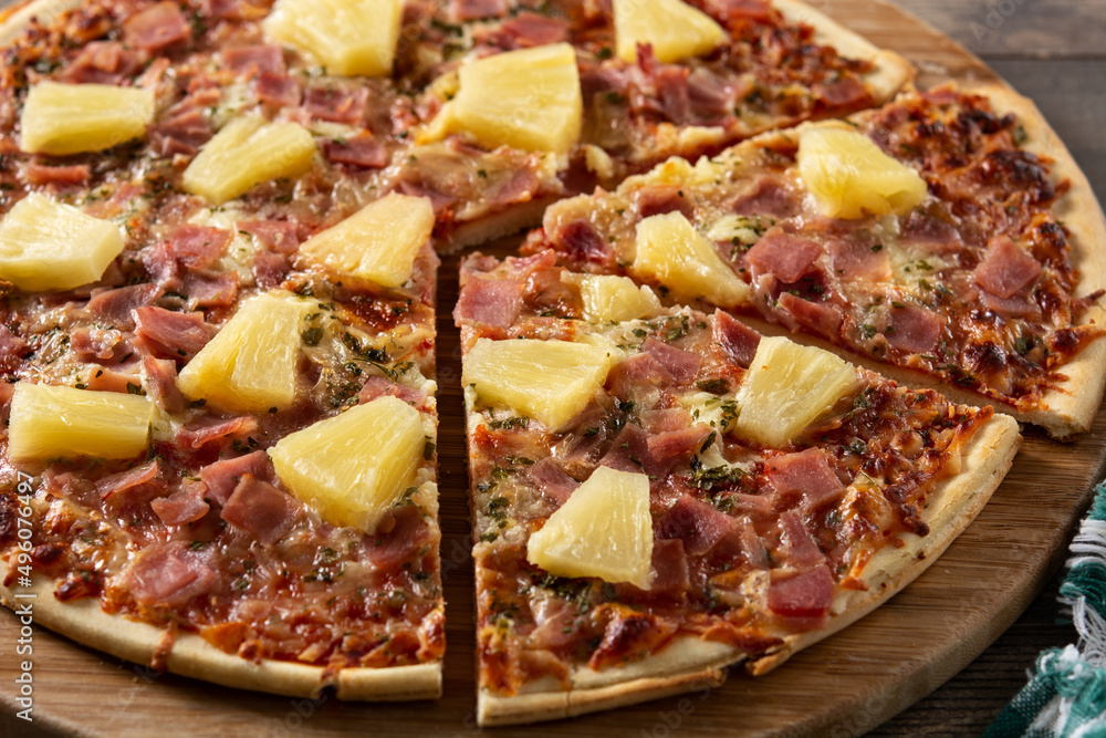 Hawaiian pizza with pineapple,ham and cheese on wooden table Hawaiian pizza with pineapple,ham and cheese on wooden table