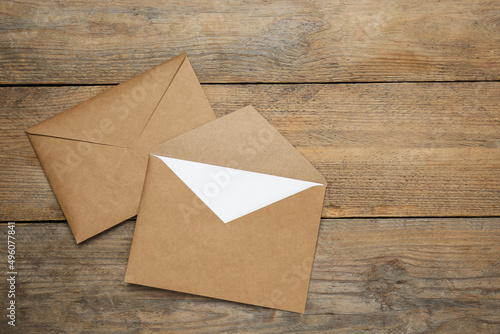 Envelopes with blank paper card on wooden table, flat lay. Space for text