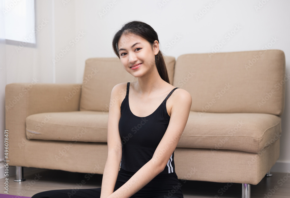Young beautiful asian woman sitting pose smiling to camera. Cheerfully sporty female workout and exercise wearing sport wear at home. Charming woman fitness training and stretching on yoga mat. Young beautiful asian woman sitting pose smiling to camera. Cheerfully sporty female workout and exercise wearing sport wear at home. Charming woman fitness training and stretching on yoga mat.