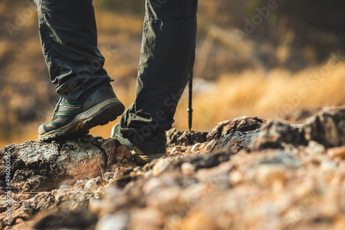 Close up mountaineering boots walking on rocky mountains at outdoor. Tourist walks on adventure trip in natural at holidays. Travel lifestyle concept