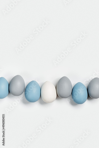 Painted Easter eggs blue, gray colored in row on white background with copy space. Chicken egg natural pastel shades. Easter holiday food, minimal design aesthetic flat lay