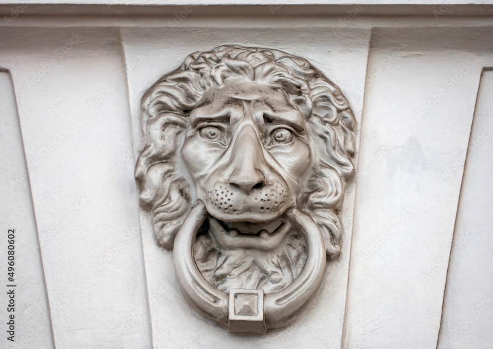 Lion is bas-relief mask with ring in its teeth on the wall of historical building.