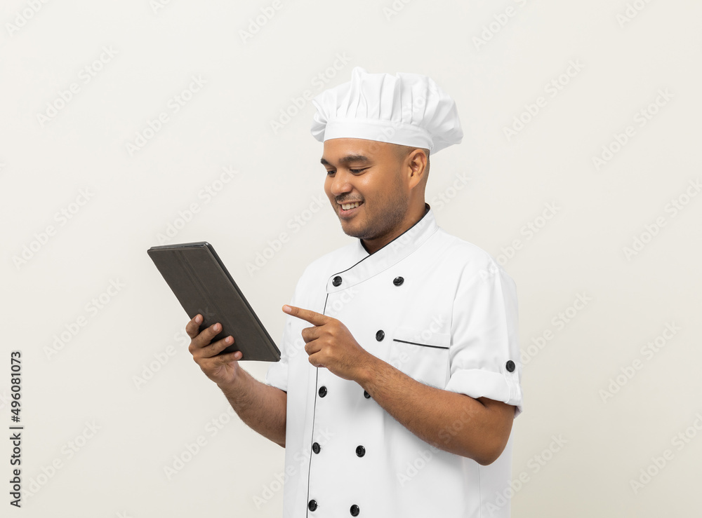 Young asian male chef holding digital tablet thinking to choose various delicious dish menu good taste for customer order. Online delivery food buying variety of dish Young asian male chef holding digital tablet thinking to choose various delicious dish menu good taste for customer order. Online delivery food buying variety of dish