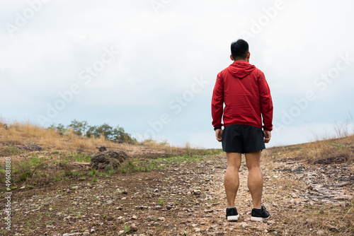 Rear view Trail runner man running on rocky mountain. Athlete jog exercising outdoor for healthy. Confident and powerful marathon man running workout and cardio. Sport and Lifestyle concept.
