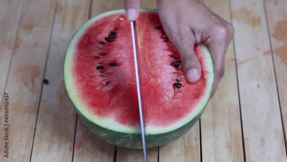 Cutting and opening a Watermelon.The flesh inside is bright red with many black small seeds. Healthy fresh berry. Close up Cutting and opening a Watermelon.The flesh inside is bright red with many black small seeds. Healthy fresh berry. Close up
