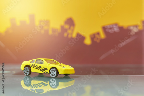 Fototapeta Naklejka Na Ścianę i Meble -  yellow racer car toy selective focus on blur city background