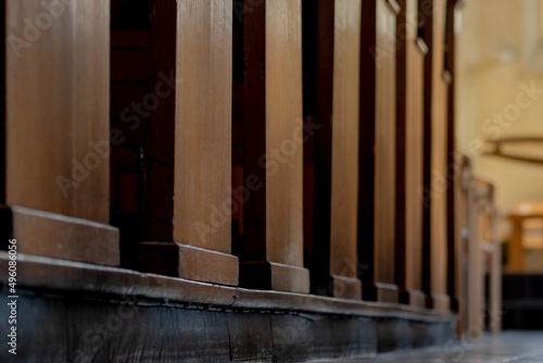 Selective focus the side of bench in the church between corridor with the sunlight  Inside the building with a row and lines of brown wooden pews in catholic church or chapel.