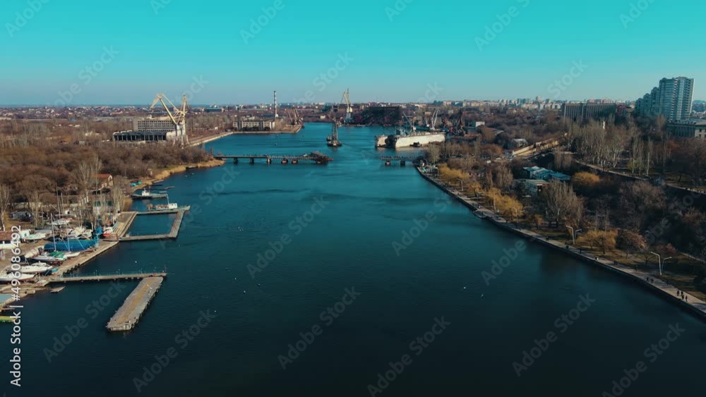 Harbor of shipbuilding city with beginning of pedestrian traffic on bridge over river. Concept of logistics of roads and waterways Harbor of shipbuilding city with beginning of pedestrian traffic on bridge over river. Concept of logistics of roads and waterways
