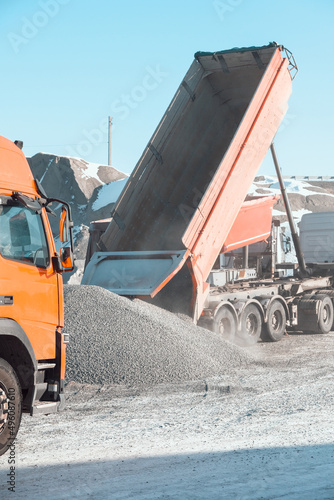 trucks carry and unload crushed stone at an asphalt concrete plant, which is needed for road construction