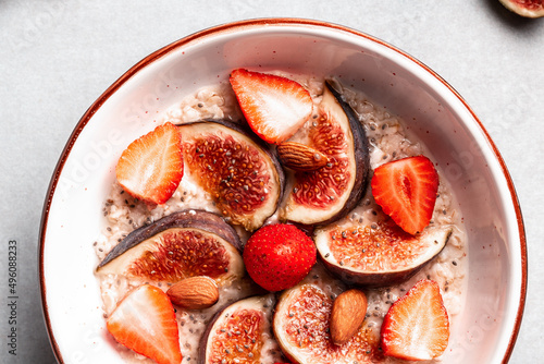 Delicious oatmeal  decorated with fig pieces  strawberries and chia seeds in a bowl  Healthy breakfast Gluten  lactose free  Fitness food. Long banner format  top view