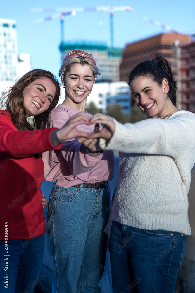 Fototapeta premium three female friends making heart shape from hand