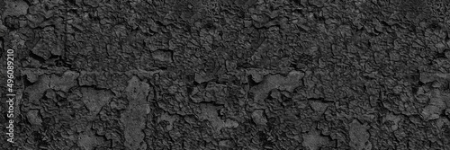 Black weathered wall wide texture. Old cracked peeling paint surface panorama. Gloomy dark abstract grunge banner background