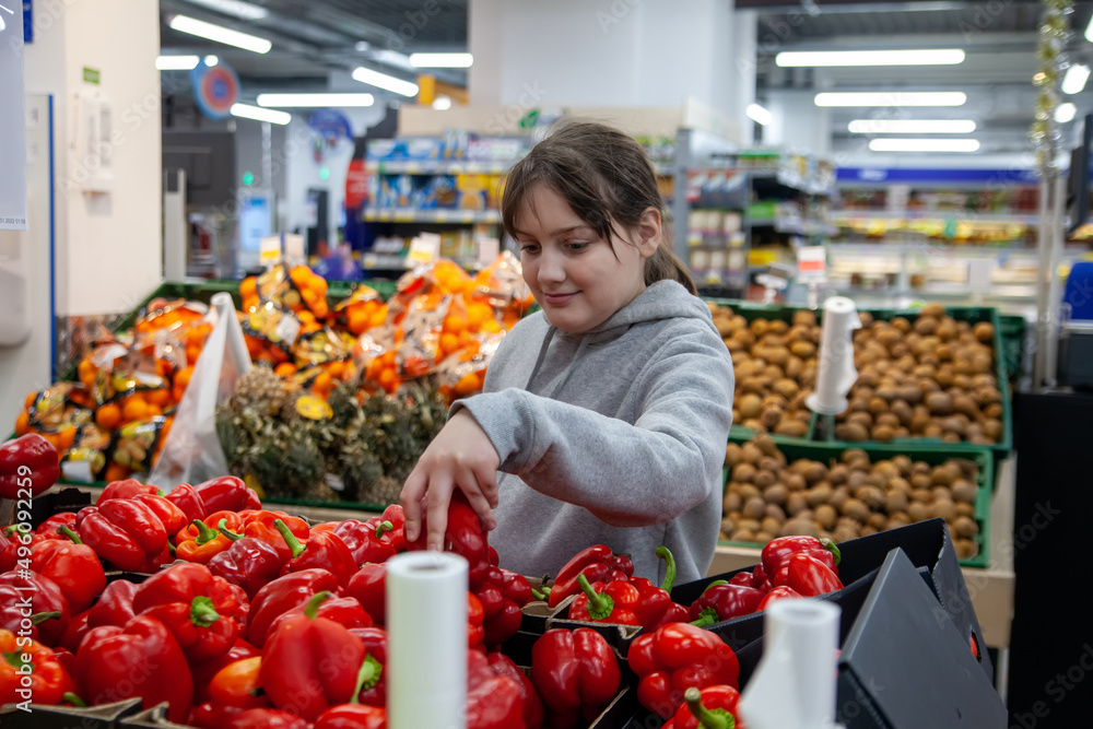 Young positive teen girl consumer  at grocery section of supermarket