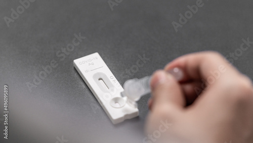 A hand dripping the extraction liquid on the cassette of a rapid antigen test 