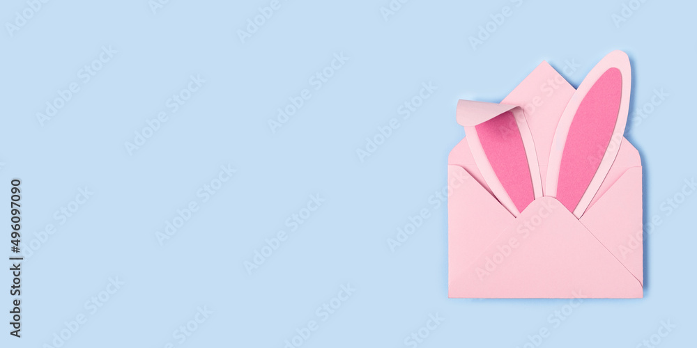Happy Easter. Bunny rabbit ears made of pink paper in pink envelope on blue background Happy Easter. Bunny rabbit ears made of pink paper in pink envelope on blue background
