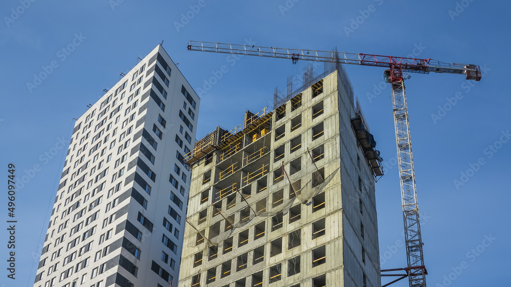 New residential building and construction building big hoisting tower crane. Highrise Construction Cranes. Construction of multi-storey buildings and business centers using a crane.