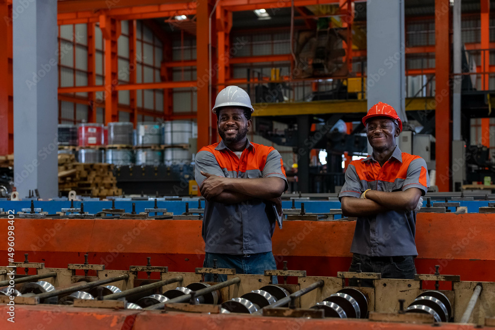 Smiling African engineers and workers with their arms crossed in an industrial factory.