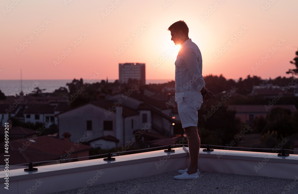 an elderly businessman in casual clothes enjoys the roof of his house at sunset time. Selective focus an elderly businessman in casual clothes enjoys the roof of his house at sunset time. Selective focus
