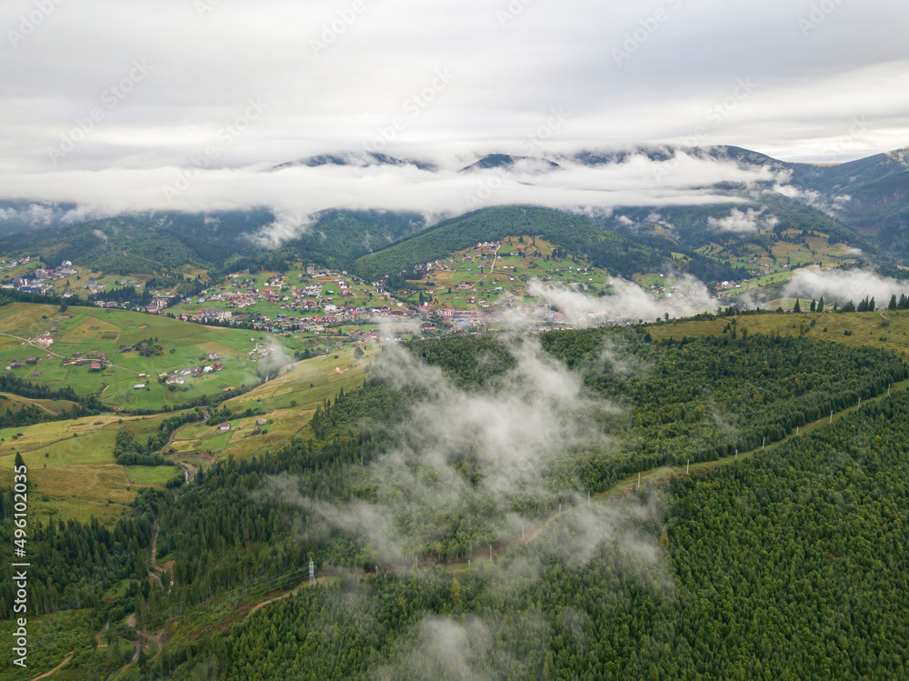 Obraz premium Green slopes of Ukrainian Carpathian mountains in summer. Cloudy morning, low clouds. Aerial drone view.