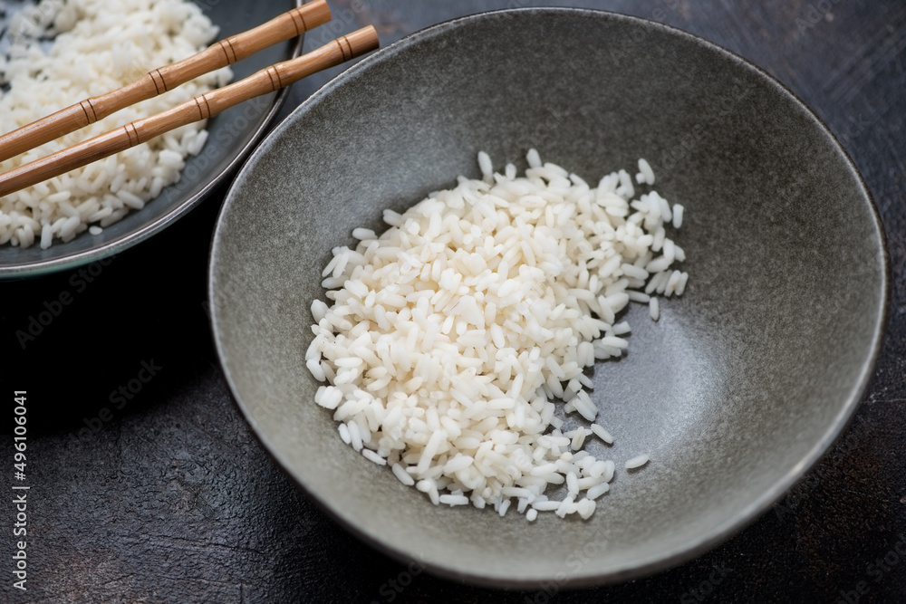 Grey plate with steamed white rice on a dark-brown stone background, middle close-up, horizontal shot Grey plate with steamed white rice on a dark-brown stone background, middle close-up, horizontal shot