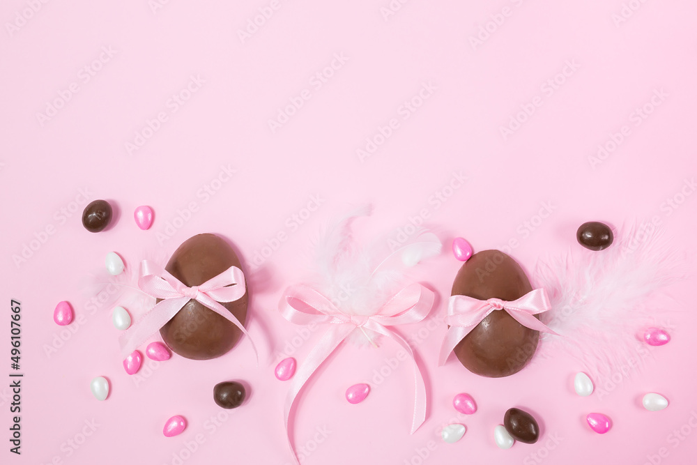 Colorful Easter chocolate eggs, flat lay on pink background. Happy Easter. Stylish Easter layout. Greeting card or banner template