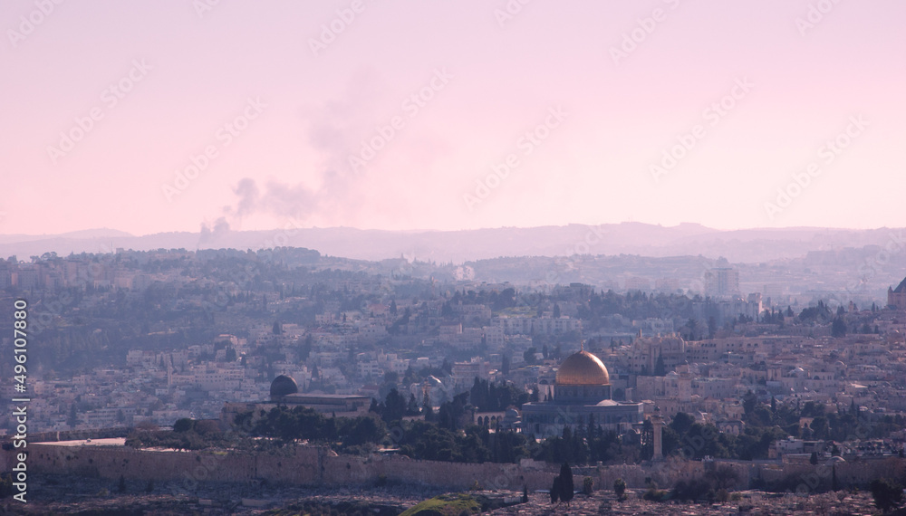 A view on n rooftops of Old City of Jerusalem and golden Dome of the Rock from Mount Scopus. Haze. Fire smoke raising at backgrounds.  Retro