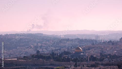 A view on n rooftops of Old City of Jerusalem and golden Dome of the Rock from Mount Scopus. Haze. Fire smoke raising at backgrounds. Retro