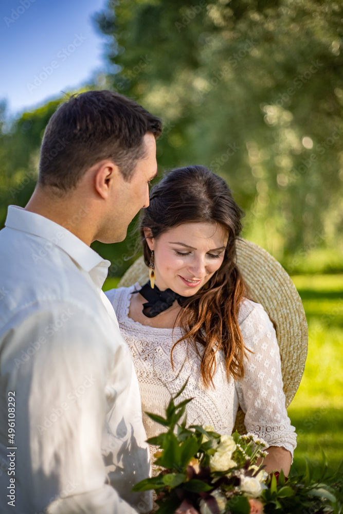 Happy young people in wedding dresses stand in the meadow and look at each other. portrait of a bride looking at a beautiful wedding bouquet Happy young people in wedding dresses stand in the meadow and look at each other. portrait of a bride looking at a beautiful wedding bouquet