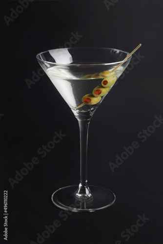 martini glass with olives on black