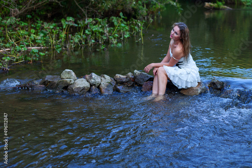 woman in white dress splashes in the river