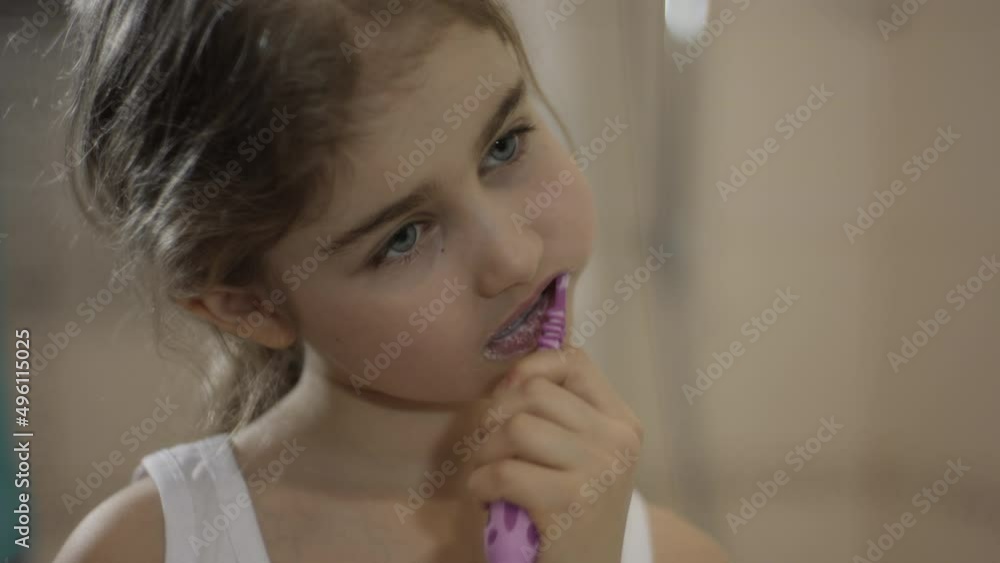 Child Brushing Teeth in Bathroom. Close-up Portrait Young Little Girl Brushing Her Teeth in Bathroom Looking at Mirror Reflection. Daily Routine Dental Hygiene. Happy Portrait Cute Caucasian Toothless Child Brushing Teeth in Bathroom. Close-up Portrait Young Little Girl Brushing Her Teeth in Bathroom Looking at Mirror Reflection. Daily Routine Dental Hygiene. Happy Portrait Cute Caucasian Toothless