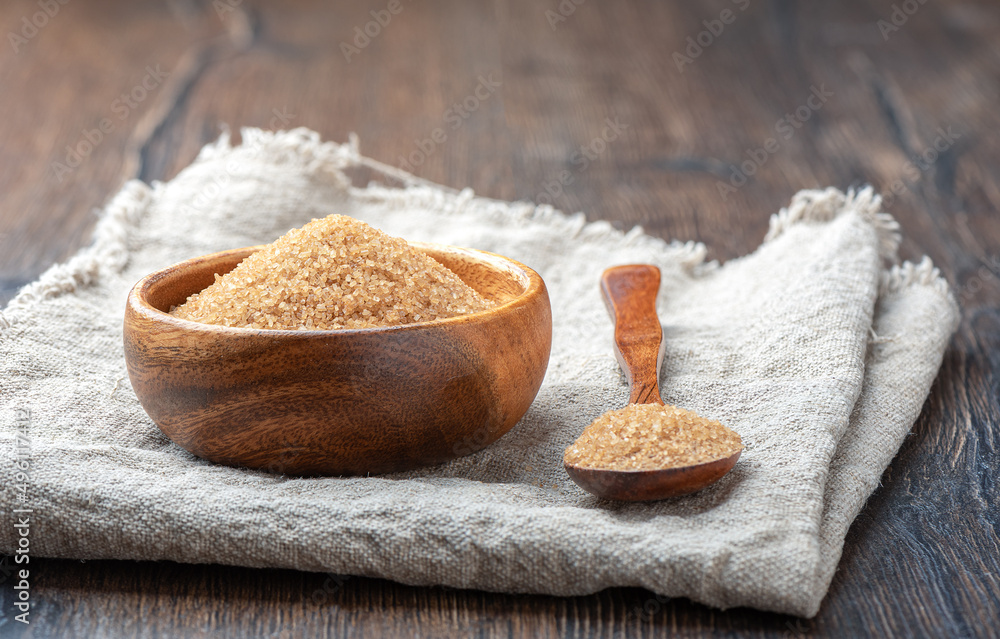 Wooden bowl and spoon with cane sugar on a coarse burlap fabric. Wooden bowl and spoon with cane sugar on a coarse burlap fabric.