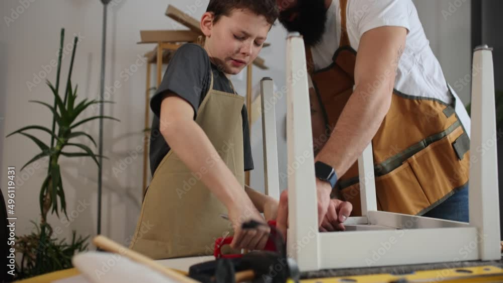 Smiling father is teaching his son of working with wood at home. Smiling father is teaching his son of working with wood at home.