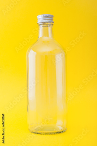 Empty glass bottle close up on a yellow background