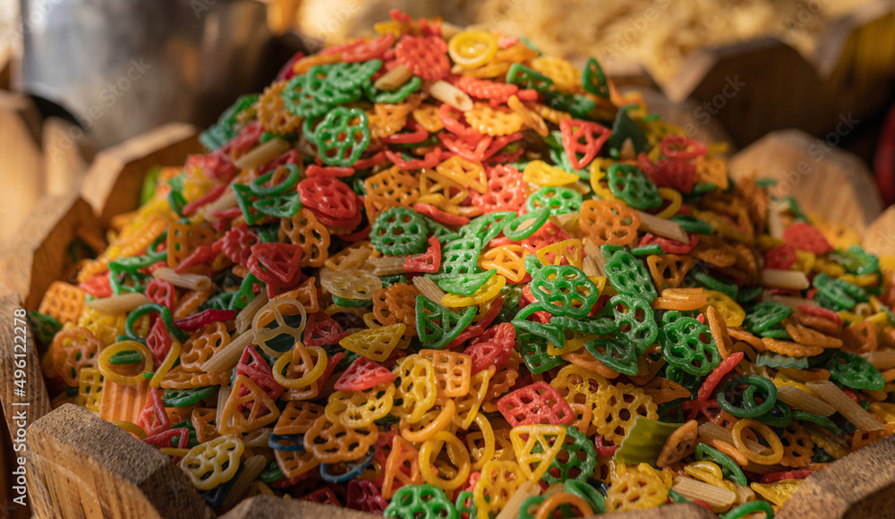 Heap of multicolored pasta on the market counter. Dramatic light