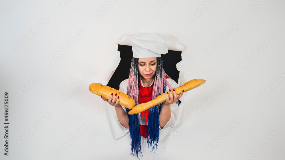 Young woman dressed as chef holding white bread. Female cook with loaf in hole of white background. Young woman dressed as chef holding white bread. Female cook with loaf in hole of white background.