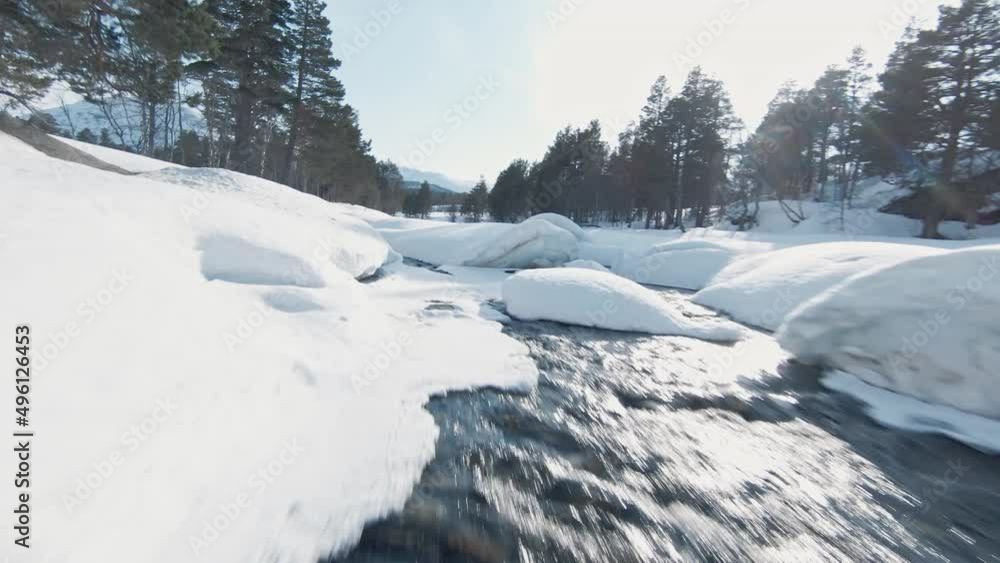Cold icy winter river in Norway landscape covered in pure white snow, FPV aerial view Cold icy winter river in Norway landscape covered in pure white snow, FPV aerial view