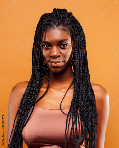 pretty young african american woman with braids posing cheerful gesturing on brown background, lifestyle people concept