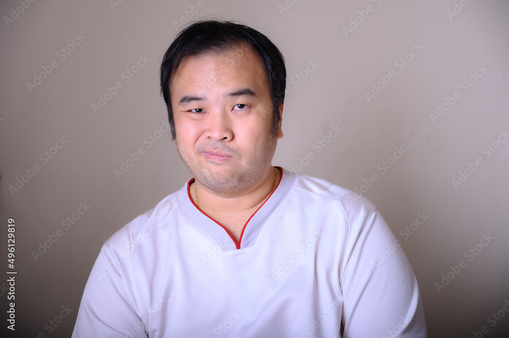 Asian men wearing white t-shirts are making a cheeky face isolated on brown background. Asian men wearing white t-shirts are making a cheeky face isolated on brown background.