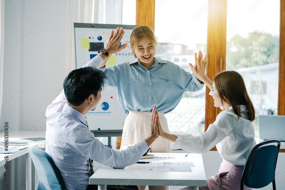 Obraz premium Young Asian business people join hands in modern meeting room.