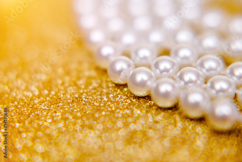 Pearl beads on a gold shiny background