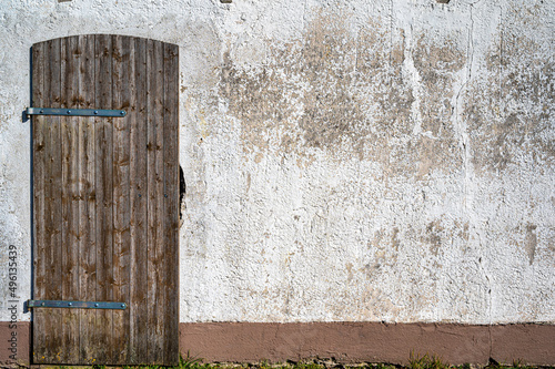 Bröckelnder Putz und gepflegte Holztür an einem alten Schuppen