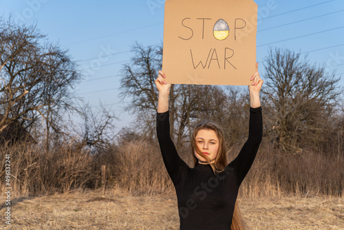 A young girl holding a poster that reads 'Stop War'. Ukrainian girl  protesting against war conflict. Stop the war in Ukraine. The concept of peace in Ukraine. Selective focus