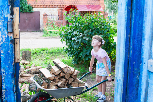 Little girl helps to carry the firewood.